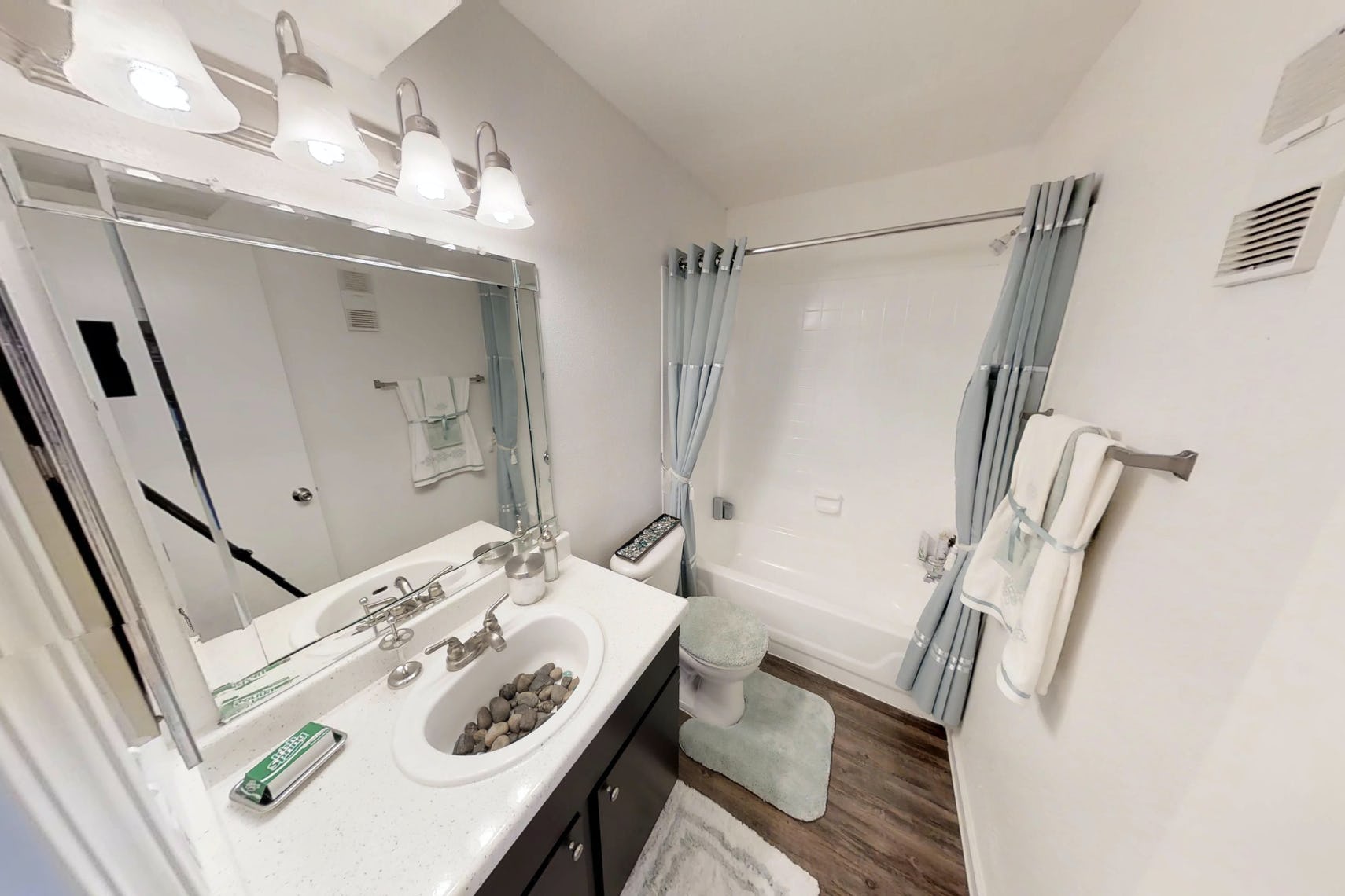 Bright bathroom at Deerbrook Apartments with a white counter and dark cabinetry. 