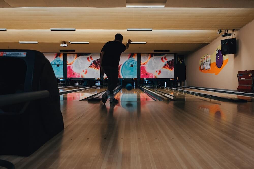 A bowling alley with someone throwing a ball down the lane.