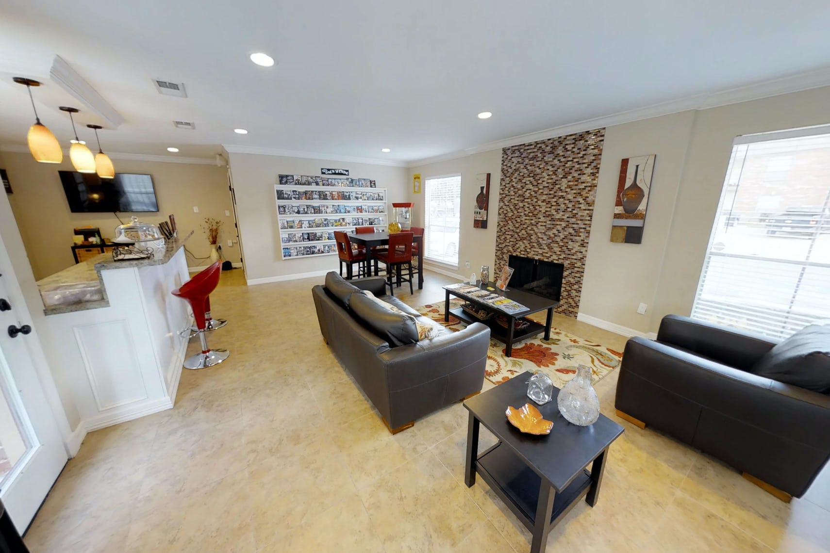 Community lounge with kitchenette on left, small square dining table, chimney, couches, and side tables.