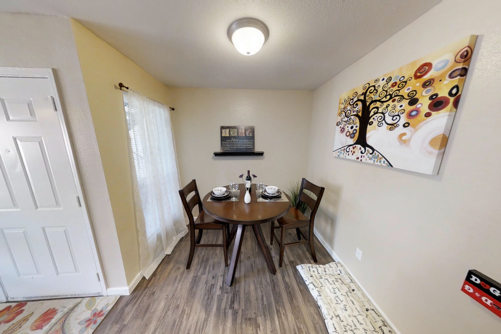 Quaint dining nook at Deerbrook Apartments with a big window beside a round, brown table and matching chairs.