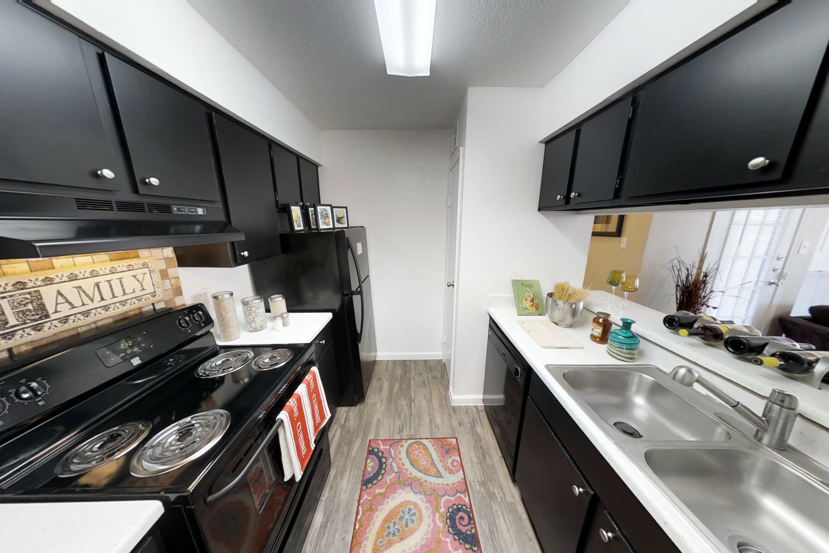 Kitchen at Deerbrooke Apartments with with countertops, black cabinets, and black appliances.