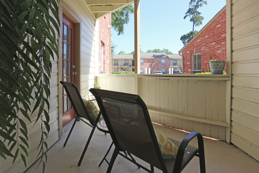 The patio at Deerbrook Apartments that comfortably fits two chairs and a side table.